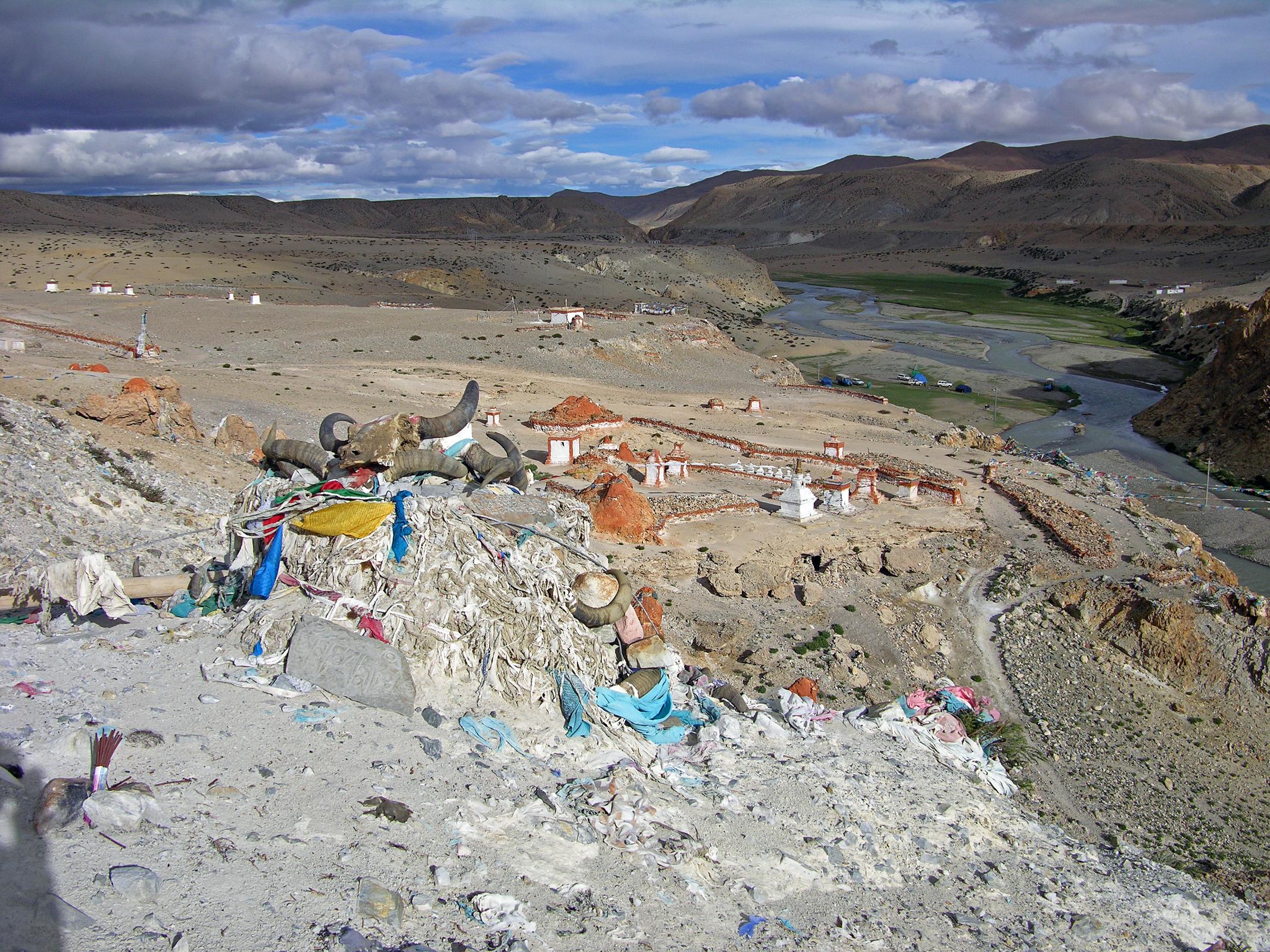 Tibet Kailash 06 Tirthapuri 11 View From Pass On Kora After the hot springs the trail climbs past a cremation area consecrated to Yeshe Tsogyal, and then reaches a miniature version of Kailash's D�lma La, marked with mani stones, prayer flags and a large collection of yak horns and skulls. To the left is the end of a recently constructed over 200m long mani wall, which points to the northeast directly towards Mount Kailas. The wall was the end result of a demon firing an arrow at the guru. He stopped the arrow's flight and transformed it into this wall.
